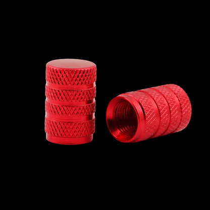 Two red anodized aluminum wheel valve stem caps with knurled textures, one standing upright and the other lying on its side to show the threaded interior, on a white background.