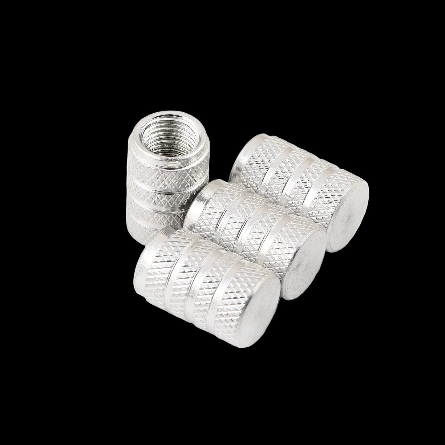 Four silver metal tire valve stem caps with knurled textured sides and smooth flat ends, shown on a clean white background.