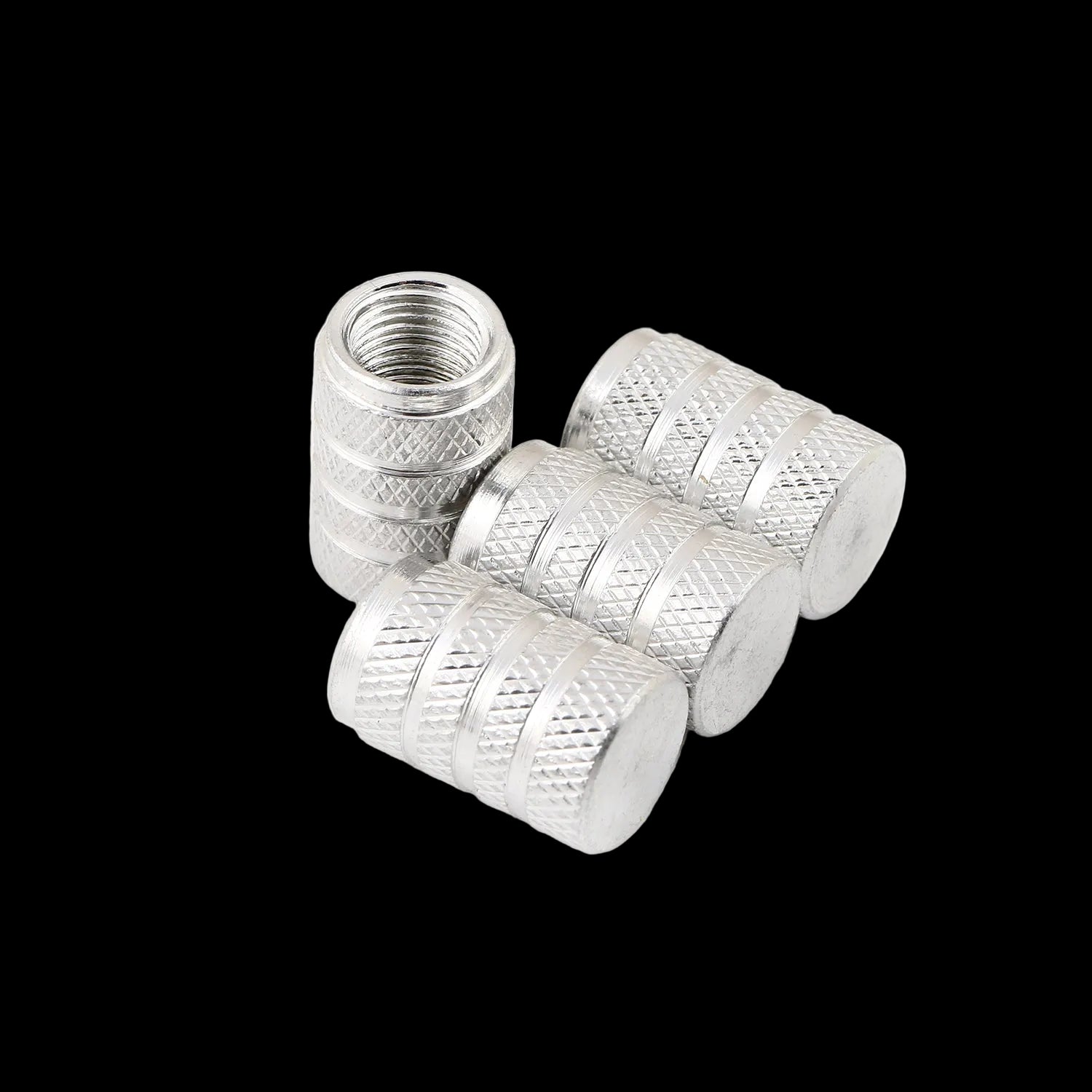 Four silver metal tire valve stem caps with knurled textured sides and smooth flat ends, shown on a clean white background.