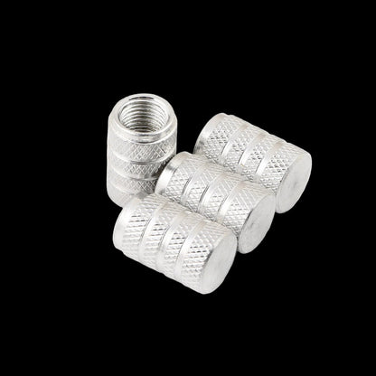 Four silver metal tire valve stem caps with knurled textured sides and smooth flat ends, shown on a clean white background.